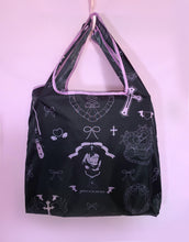 Load image into Gallery viewer, Black tote bag with light pink designs on a pink background